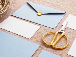 modré a biele obálky na hnedom podklade s nožnicami