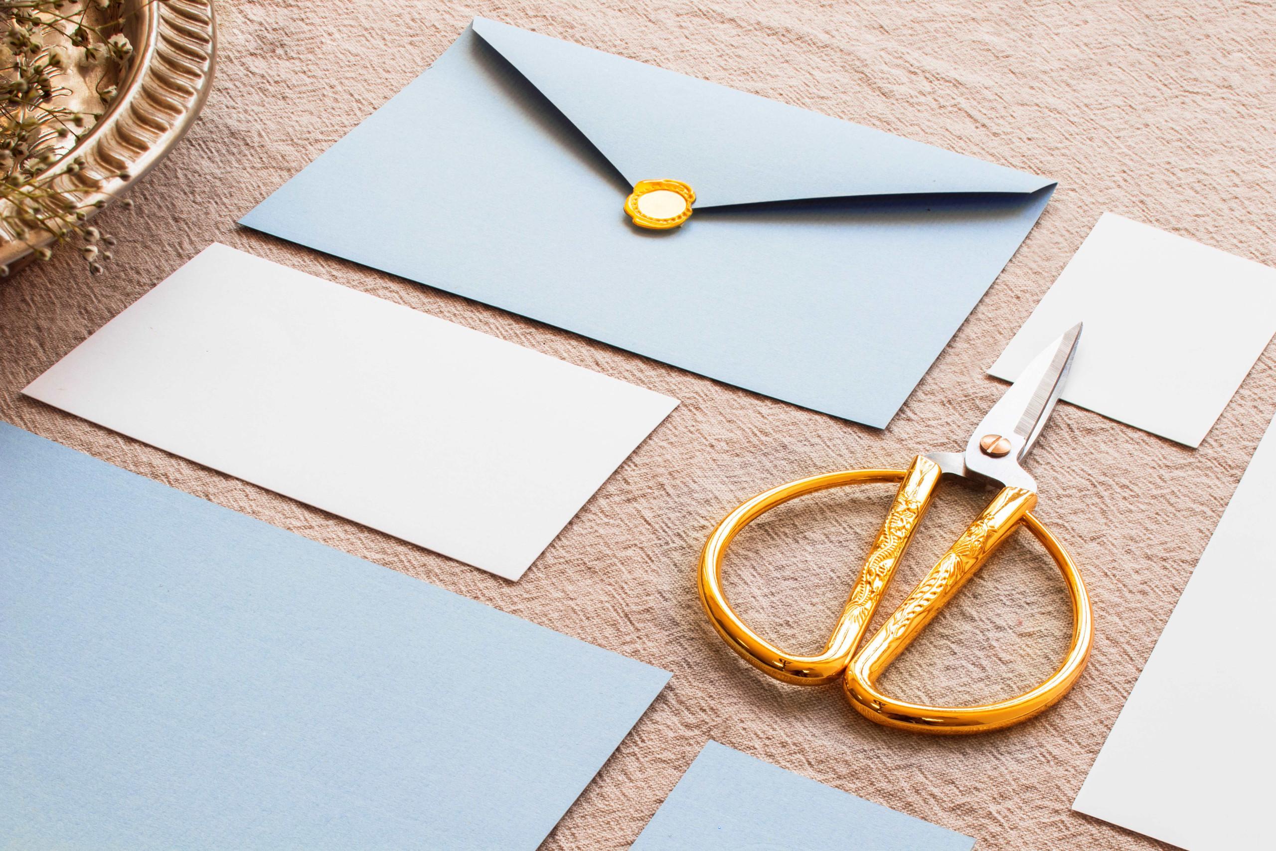 modré a biele obálky na hnedom podklade s nožnicami